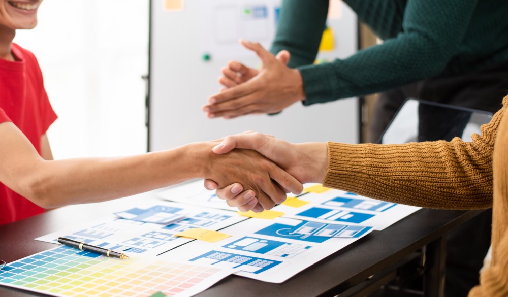 2 design professional shaking hands while other claps