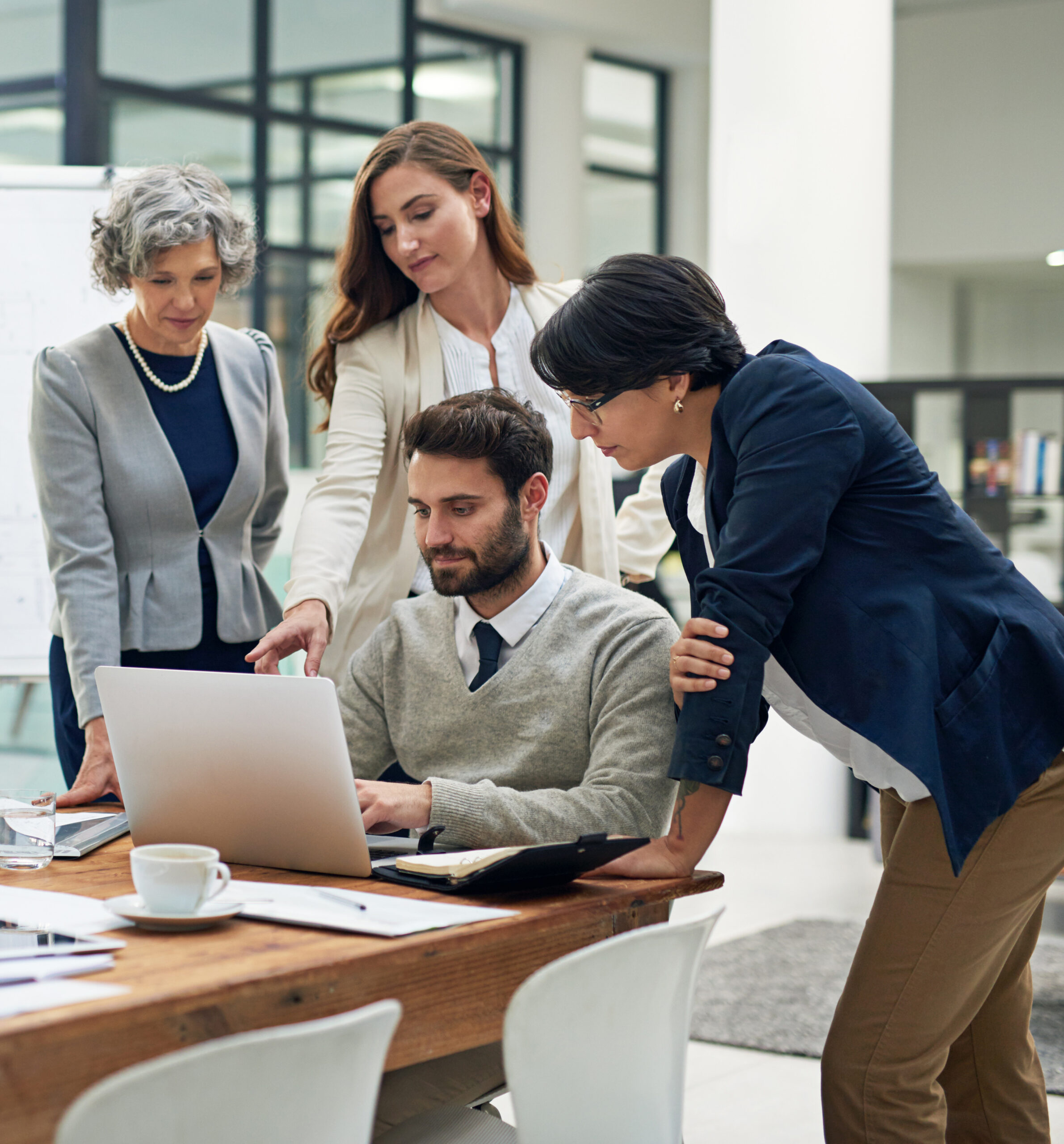 3 lady looking at the screen while 1 man is sitting and browsing the laptop