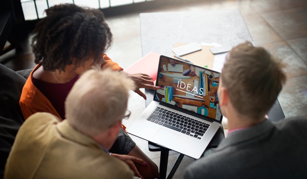 three people looking on a laptop screen displaying Ideas