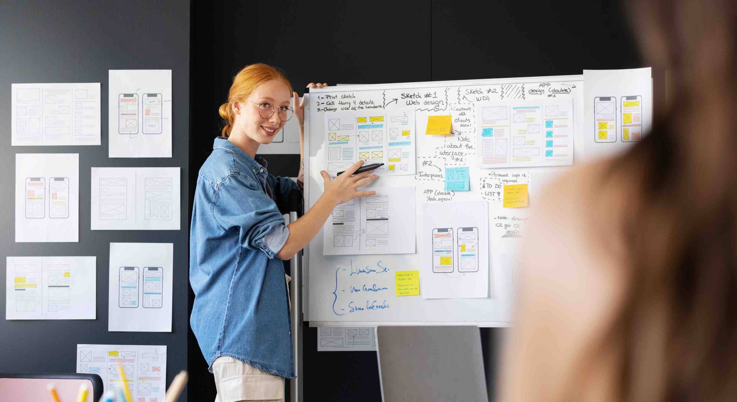 Happy lady showing wireframe pinned on notice board
