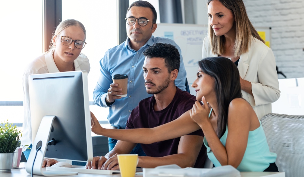 Five professional looking together on a computer