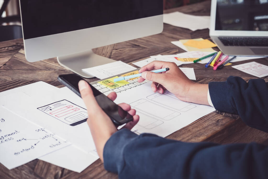 A designer at his desk working on a website design for mobile