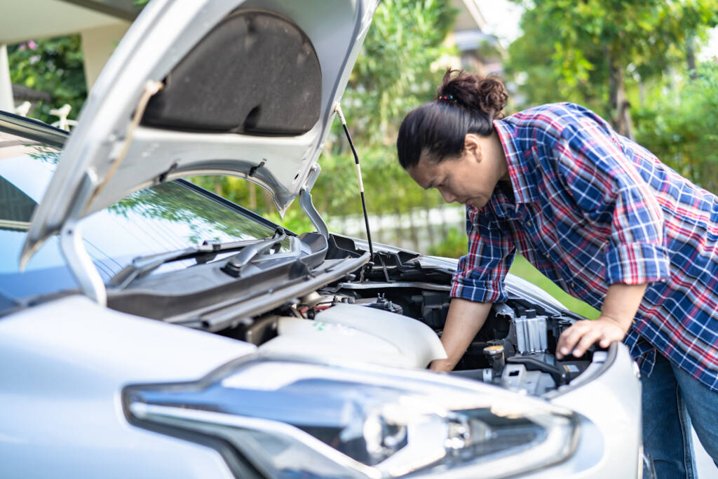 A man lookin under the hood of car