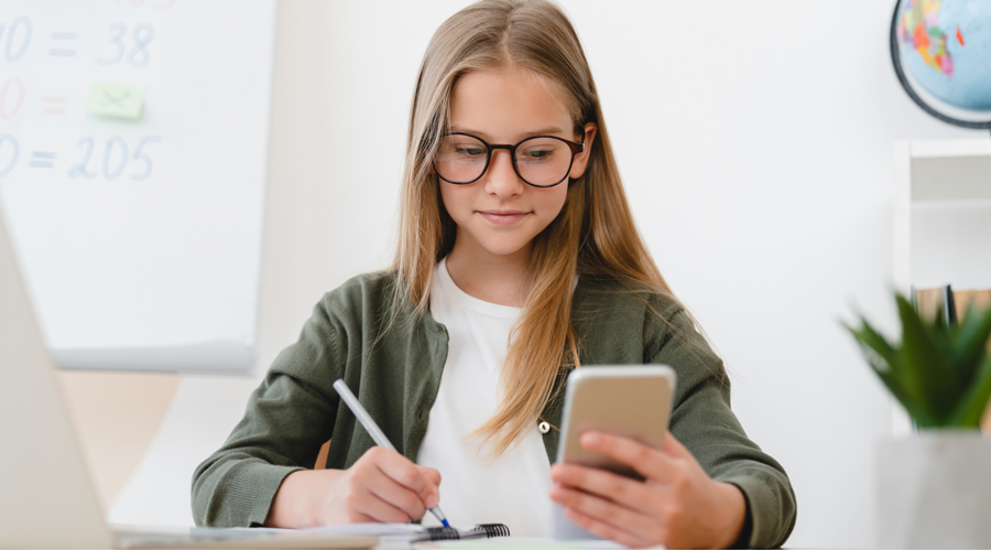 Girl writing something while looking at the phone screen