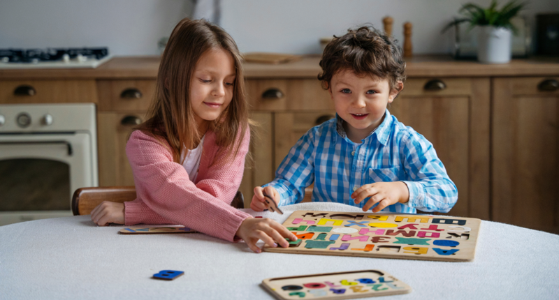 2 kids a boy and girl having fun while playing with alphabets puzzles