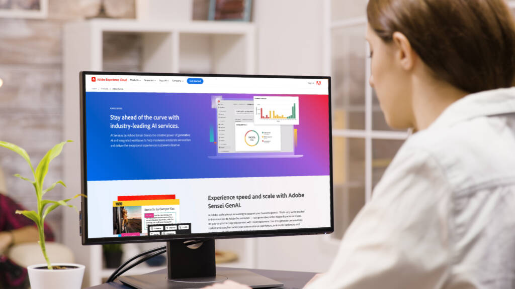 A woman looking at computer displaying Adobe Sensei website