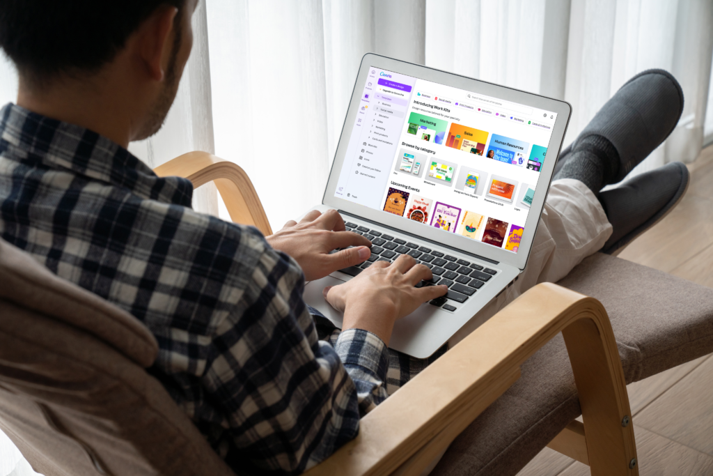 A Man looking at laptop displaying Canva website