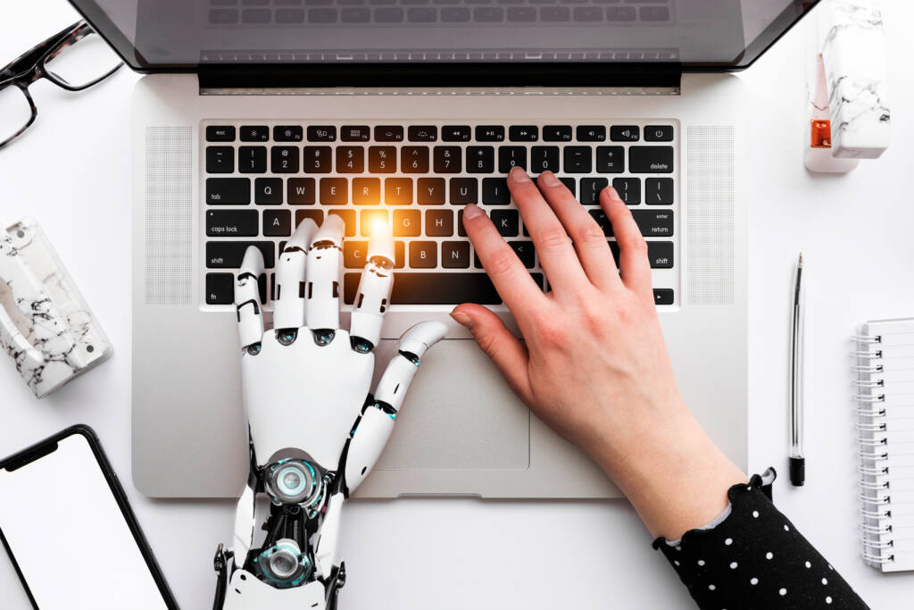 Robot and human hand on a laptop