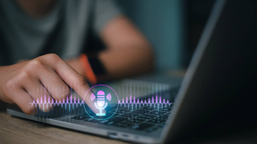 A finger pressing laptop keyboard and voice is displayed virtually