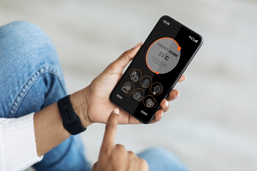 Hands regulating air conditioner using smart home mobile application on smartphone