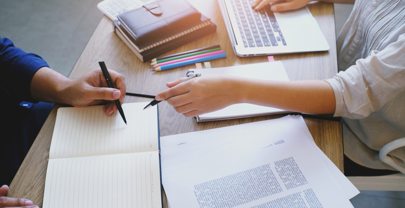 One people suggesting another to write on the notepad with laptop open
