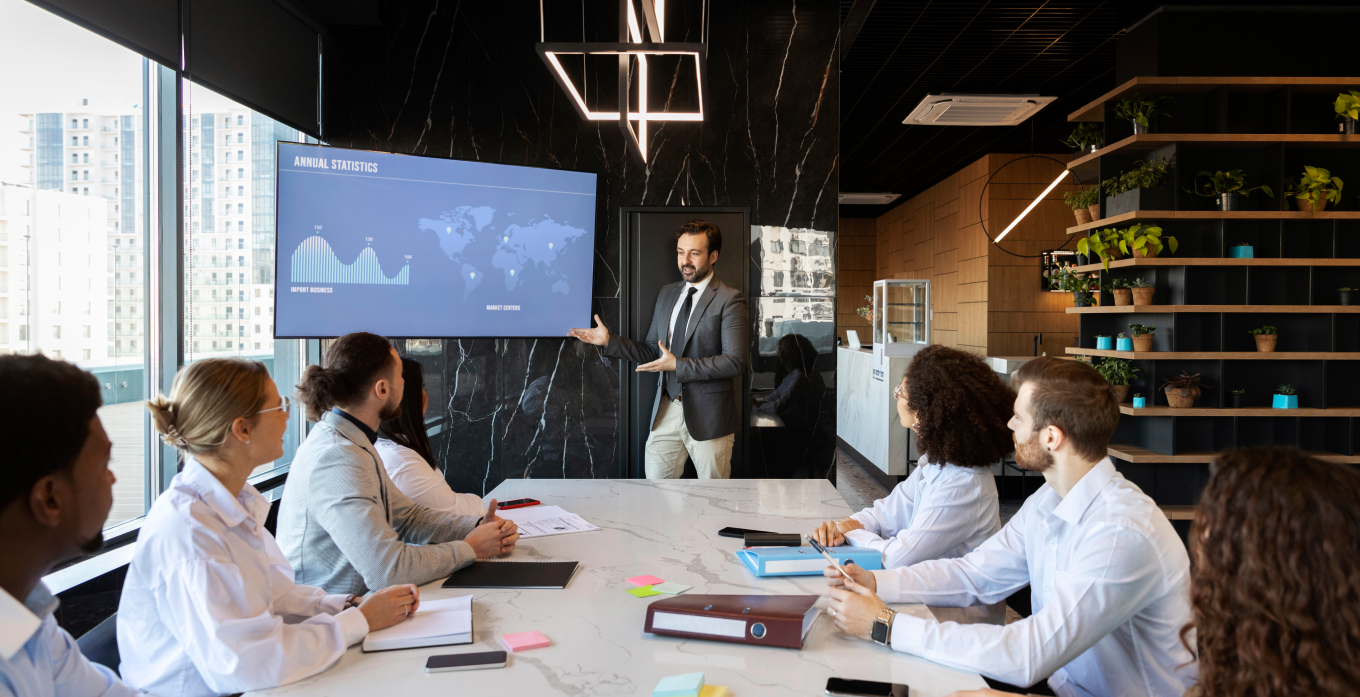 Man presenting anual statics on screen to all other people sitting in the meeting room