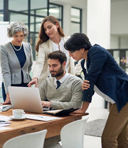 3 lady looking at the screen while 1 man is sitting and browsing the laptop
